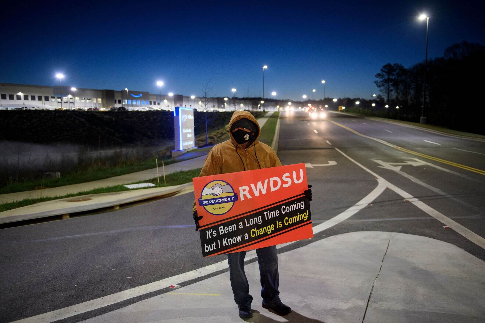 A union supporter stands before sunrise outside the Amazon.com, Inc. BHM1 fulfillment center on March 29, 2021 in Bessemer, Alabama. April 2021