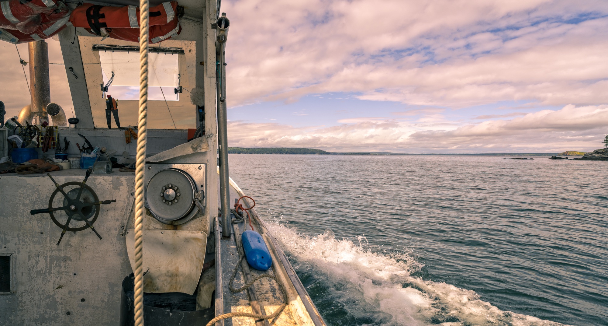 Image of Lobster boat cruising among the islands near Stonington, Maine. July 2021.