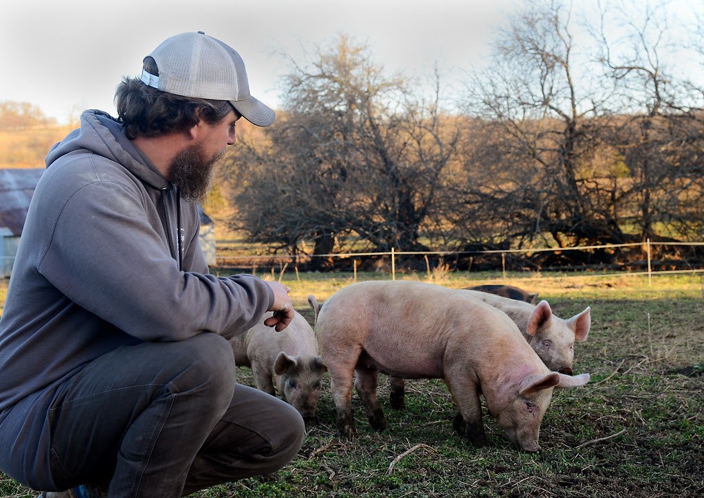 Andrew Geiser pets his pigs on Friday, March 19, 2021, in Chillicothe, Mo.
