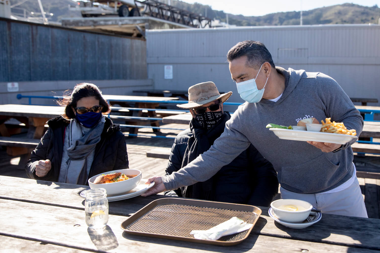 Miguel Batam serves Anoma (left) and Ajith Amerasekera of Berkeley their lunch while seated in the outside patio area at Fish restaurant in Sausalito, Calif. Monday, January 25, 2021.